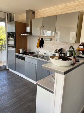 A modern kitchen with stainless steel appliances, wooden accents, and a large island with a bowl.