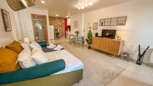 Una sala de estar moderna con un sofá, un televisor y un comedor con una mesa y sillas.