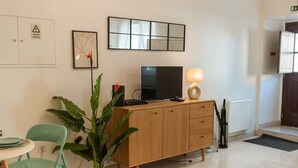 Una sala de estar moderna con un aparador de madera, un televisor, una lámpara y una planta en maceta.