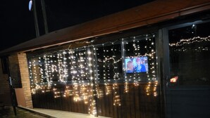 A building facade with a brick wall and a large window displaying a television screen. - Moding apartmans (Dobroshane)