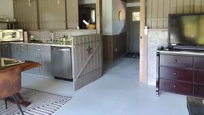 Een moderne keuken met grijze kastjes, roestvrijstalen apparatuur en een houten eettafel.