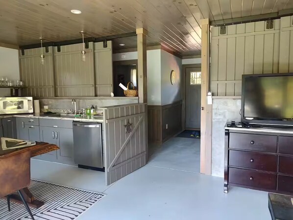 A modern kitchen with grey cabinets, stainless steel appliances, and a wooden dining table.