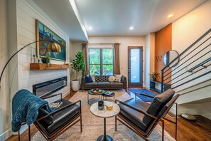 A modern living room with a fireplace, a sofa, a coffee table, and a staircase. - Stylish RiNo Townhome with Rooftop Patio Walkable to Downtown, Larimer, Ballpark (Denver)