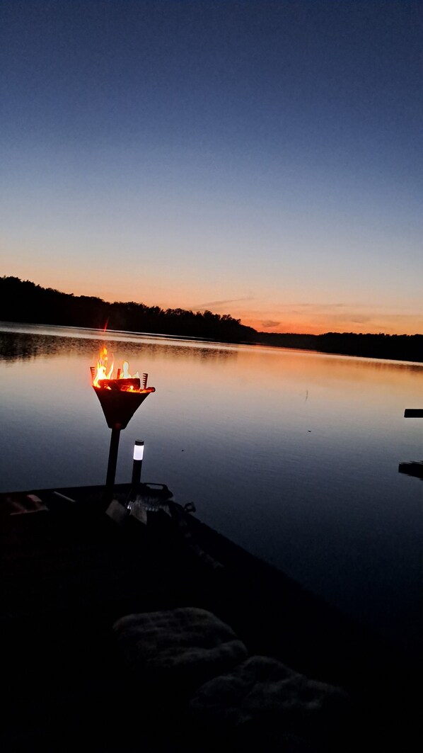 Une scène paisible au bord du lac, au crépuscule, avec un foyer installé sur le quai.