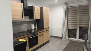 Une cuisine moderne avec des meubles en bois, un plan de travail noir et un four encastré.