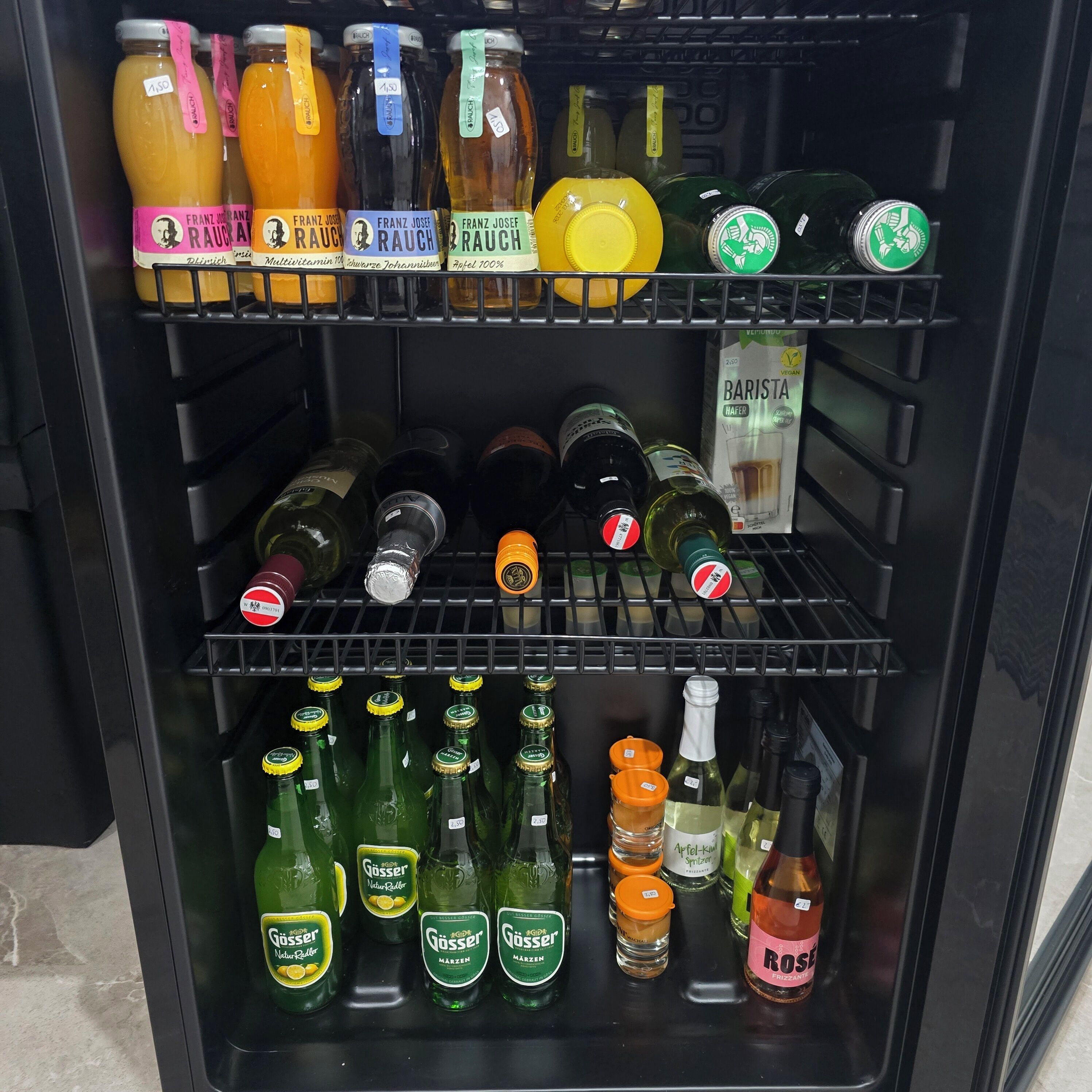 A refrigerated display case with various beverages including juices, beers, and wines.