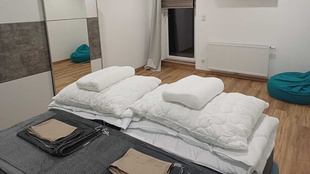 Une chambre moderne avec un lit, un miroir, une télévision, une fenêtre avec des rideaux et un radiateur.