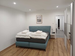 A modern bedroom with a teal upholstered bed, white bedding, and a framed picture on the wall. - "Vacations on the sunny side of the Semmering in Breitenstein" (Breitenstein)