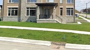 A two-story residential building with a stone facade, multiple windows, and a front porch. - Secluded Tranquil 4 Bedroom Property (Oshawa)