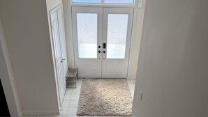 A staircase leading to a door with frosted glass panels, a white rug on the floor, and a light fixture above. - Secluded Tranquil 4 Bedroom Property (Oshawa)