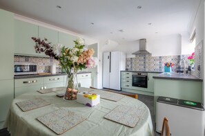 Una cocina moderna con una mesa de comedor, un jarrón de flores y un cubo de basura.