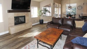 Ett rymligt vardagsrum med en öppen spis, en soffa i läder och en tv som är monterad på väggen.
