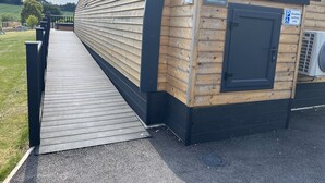 Een houten gebouw met een hellingbaan naar een deur, een bord met de tekst 'Blackbird Lodge' en een gehandicaptenparkeerplaats.