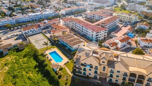 Vue aérienne d’un quartier résidentiel situé sur la côte, avec de nombreux immeubles, dont un grand hôtel doté d’une piscine et offrant une vue sur la mer.