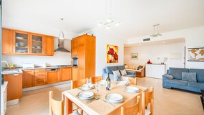 Une cuisine moderne avec des meubles en bois, une table à manger pour quatre personnes et un coin salon avec un canapé et une table basse.