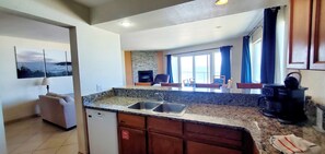 A kitchen with a granite countertop, a dishwasher, and a coffee maker. - Condo #208 with beautiful sunset view from your balcony overlooking the ocean (Lincoln City)