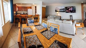A modern living room with a sofa, a dining table with chairs, a kitchen area, and a fireplace. - Condo #208 with beautiful sunset view from your balcony overlooking the ocean (Lincoln City)