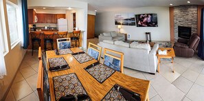 Ein modernes Wohnzimmer mit einer Couch, einem Esstisch mit Stühlen, einer Küchenzeile und einem Kamin.
