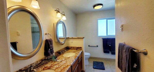A bathroom with two sinks, a large mirror, and a window. - Condo #208 with beautiful sunset view from your balcony overlooking the ocean (Lincoln City)
