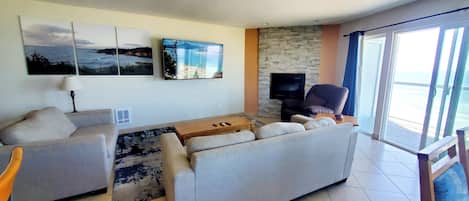 Ein Wohnzimmer mit einer Couch, einem Couchtisch und einem Flachbildfernseher an einer Steinwand.