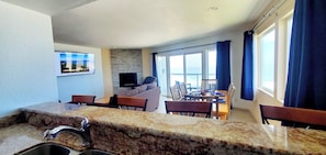 A kitchen with granite countertops, a sink, and a dining area with a table and chairs. - Condo #308 with beautiful sunset view from your balcony overlooking the ocean (Lincoln City)