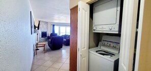 Ein Waschraum mit Waschmaschine und Trockner, ein Fliesenboden und ein Wohnbereich mit Sofa und Kamin.