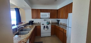 A compact kitchen with granite countertops, wooden cabinets, a white stove, a microwave, and a refrigerator. - Condo #308 with beautiful sunset view from your balcony overlooking the ocean (Lincoln City)