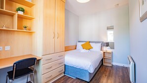 Ein Schlafzimmer mit Bett, Schreibtisch, Stuhl, Kleiderschrank und Nachttisch.