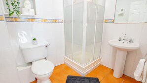 Ein Badezimmer mit Toilette, Duschkabine aus Glas und Waschbecken.