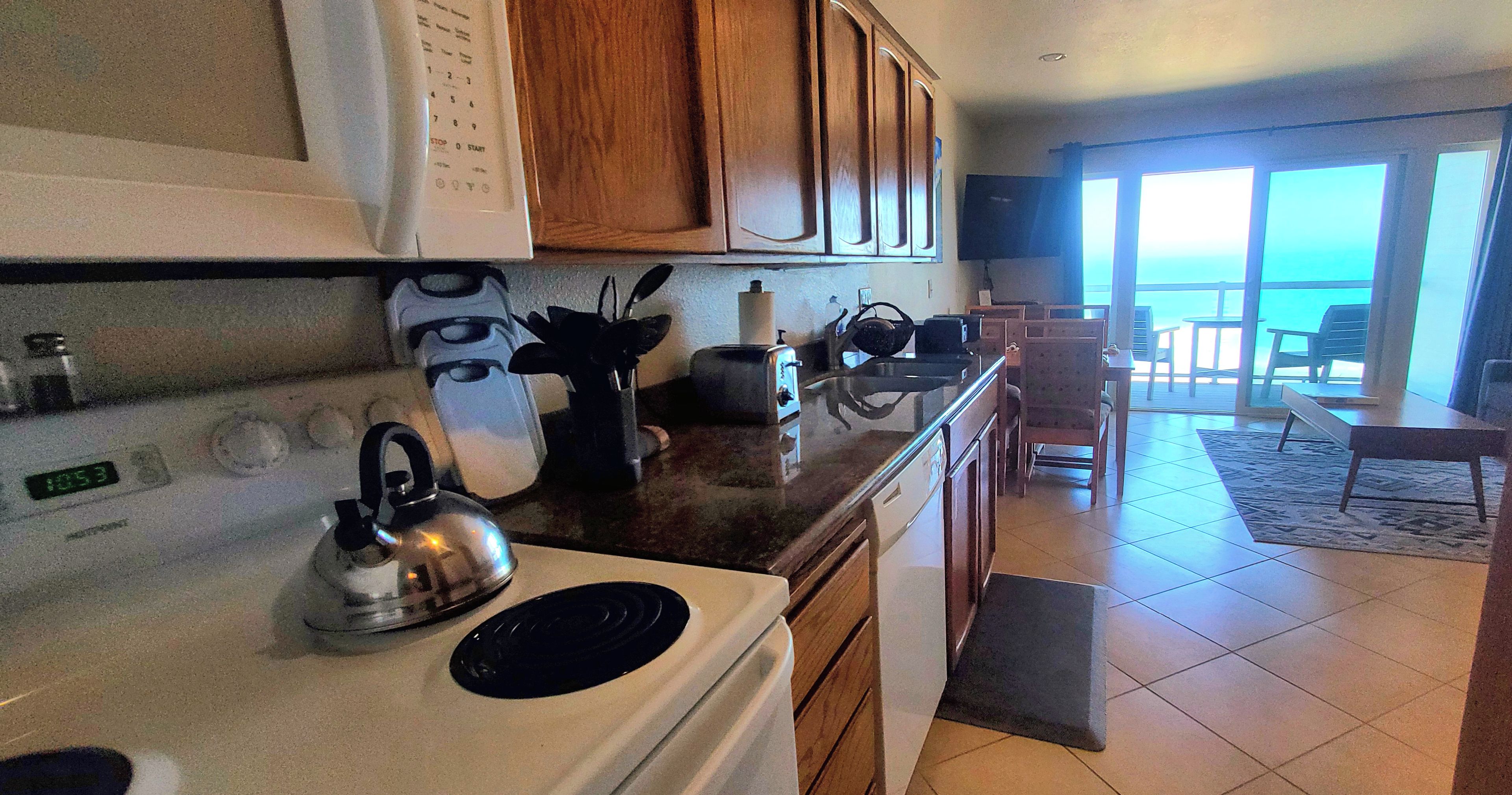 A kitchen with a stove, kettle, toaster, and wooden cabinets.