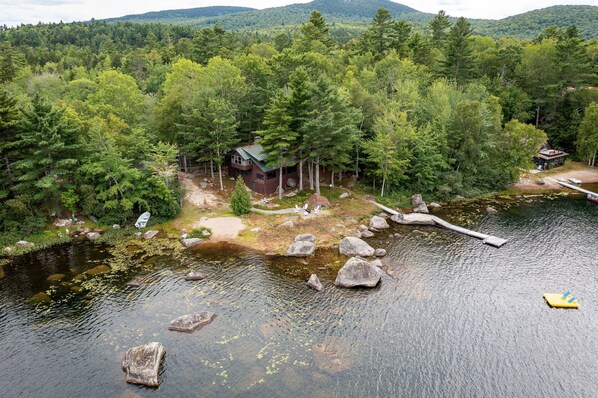 Eine Hütte, umgeben von dichtem Wald und einem See.