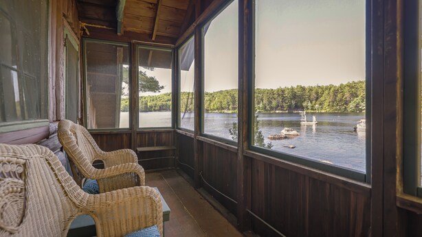 A wooden deck with wicker furniture overlooking a lake. - Quintessential Maine Lake House, 280Ft of Waterfront, near Acadia & Bar Harbor (Dedham)
