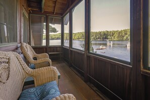 A wooden deck with wicker furniture overlooking a lake.