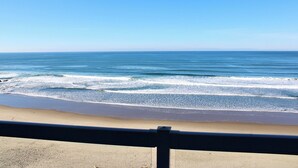 A beach with waves, a clear sky, and a railing in the foreground. - Condo #204 with beautiful sunset view from your balcony overlooking the ocean (Lincoln City)