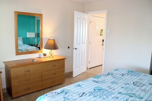 A bedroom with a bed, a dresser, a mirror, and a door leading to another room. - Condo #204 with beautiful sunset view from your balcony overlooking the ocean (Lincoln City)