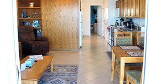 A living room with a brown sofa, a wooden bookshelf, and a dining area with a wooden table and chairs. - Condo #204 with beautiful sunset view from your balcony overlooking the ocean (Lincoln City)