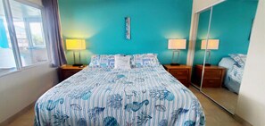 A bedroom with a bed, two bedside tables, a mirror, and a window. - Condo #108 with beautiful sunset view from your balcony overlooking the ocean (Lincoln City)