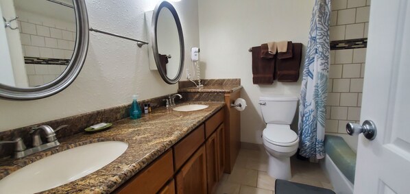 A bathroom with two sinks, a toilet, a shower curtain, and a towel rack. - Condo #108 with beautiful sunset view from your balcony overlooking the ocean (Lincoln City)