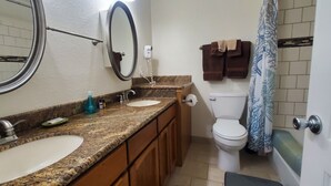 Une salle de bain avec deux lavabos, des toilettes, un rideau de douche et un porte-serviettes.