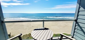 A beach view from a balcony with a table and chairs. - Condo #102 with beautiful sunset view from your balcony overlooking the ocean (Lincoln City)
