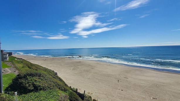 Une plage offrant une vue dégagée sur l’océan, avec un bâtiment en premier plan.