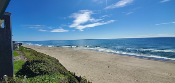 Une plage offrant une vue dégagée sur l’océan, avec un bâtiment en premier plan.