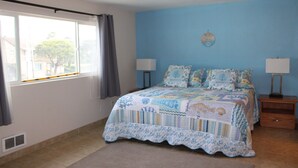 A bedroom with a bed, two bedside tables, a window with curtains, and a wall clock. - Condo #307 with beautiful sunset view from your balcony overlooking the ocean (Lincoln City)