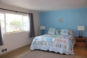 A bedroom with a bed, two bedside tables, a window with curtains, and a wall clock. - Condo #307 with beautiful sunset view from your balcony overlooking the ocean (Lincoln City)