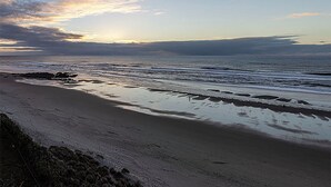 A beach with a wide sandy shore and gentle waves. - Condo #307 with beautiful sunset view from your balcony overlooking the ocean (Lincoln City)