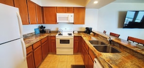A kitchen with wooden cabinets, a microwave, a stove, a sink, and a coffee maker. - Condo #307 with beautiful sunset view from your balcony overlooking the ocean (Lincoln City)