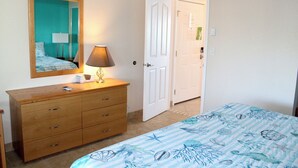 A bedroom with a bed, a dresser, a mirror, and a door leading to another room. - Condo #206 with beautiful sunset view from your balcony overlooking the ocean (Lincoln City)