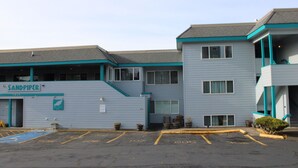 A motel with a sign reading 'Sandpiper' and numbered parking spaces. - Condo #206 with beautiful sunset view from your balcony overlooking the ocean (Lincoln City)