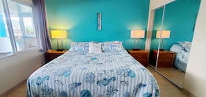 A bedroom with a bed, two bedside tables, a mirror, and a window. - Condo #203 with beautiful sunset view from your balcony overlooking the ocean (Lincoln City)