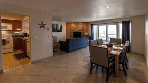 A modern kitchen with a microwave, stove, and dining area with a table and chairs. - Condo #207 with beautiful sunset view from your balcony overlooking the ocean (Lincoln City)